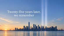 An image of the New York City skyline at sunset, with beams of light representing the World Trade Center towers.